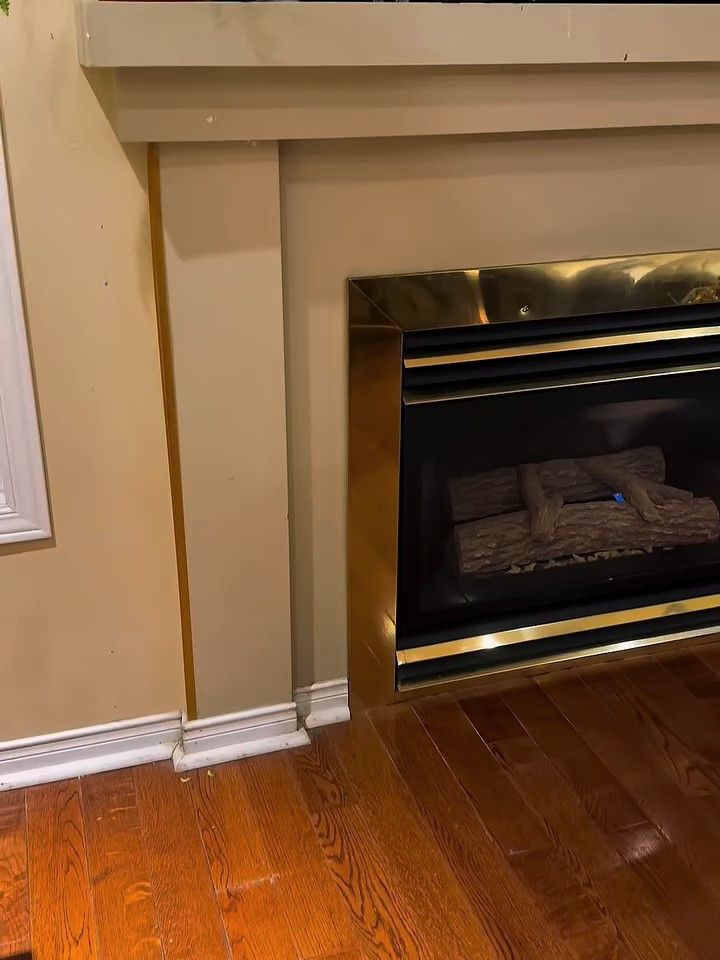 Fireplace with a painted wood surround and brass trim, before refacing