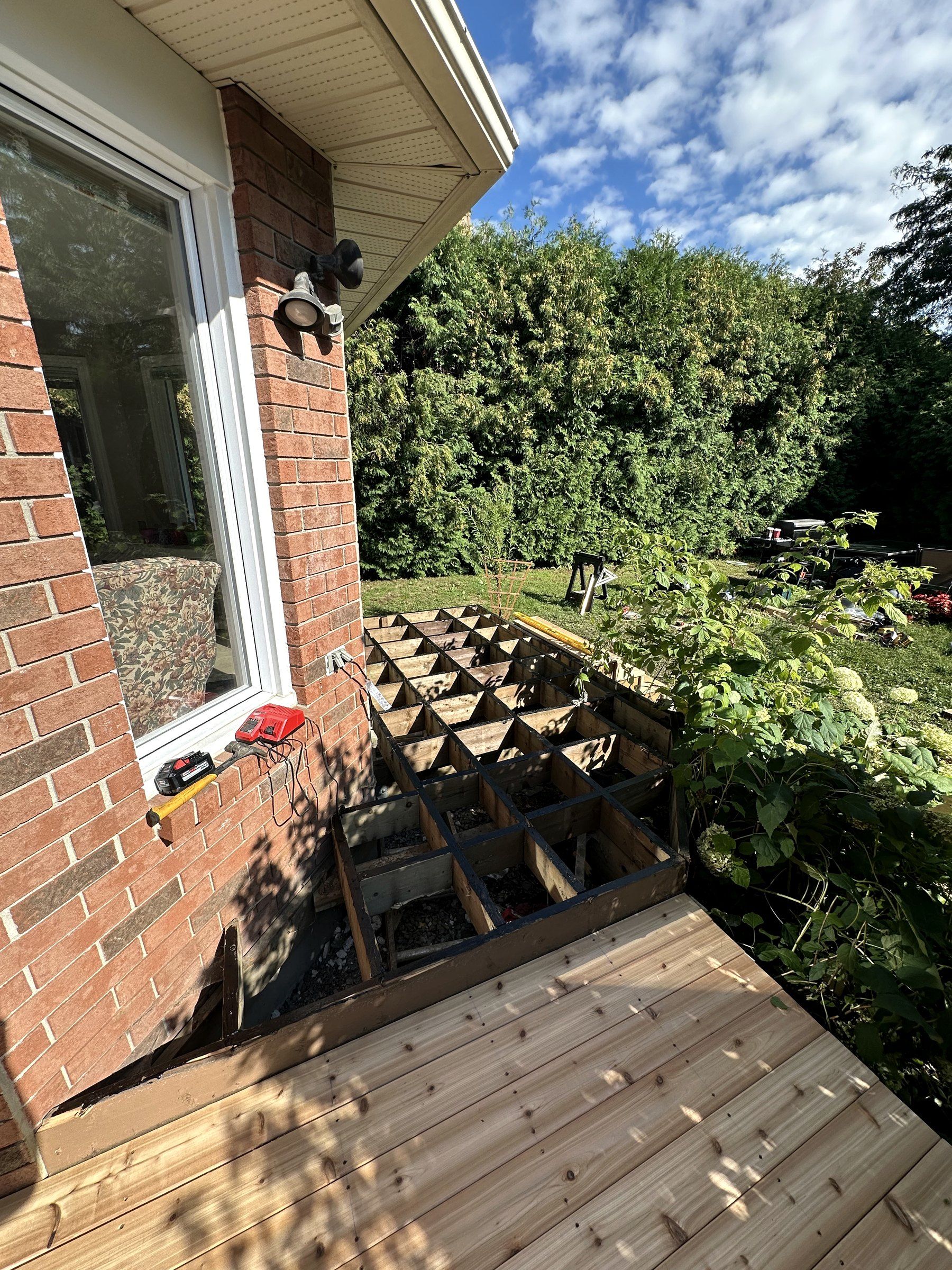 New cedar deck boards being laid over a deck frame with joist tape