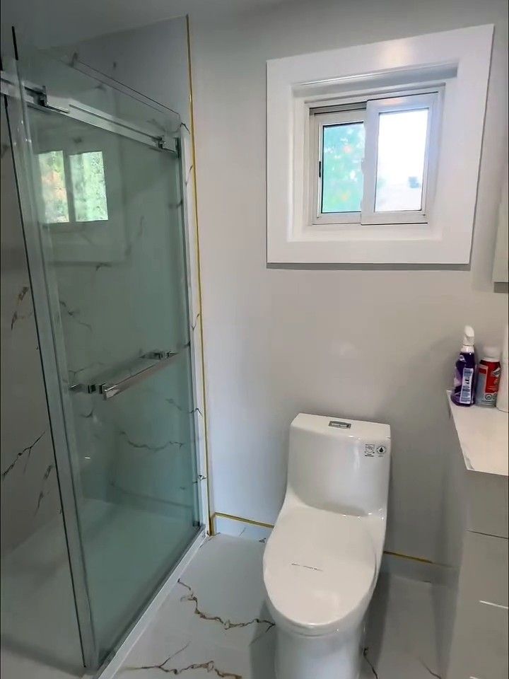 Sliding glass shower door on a tiled shower, beside a one-piece toilet