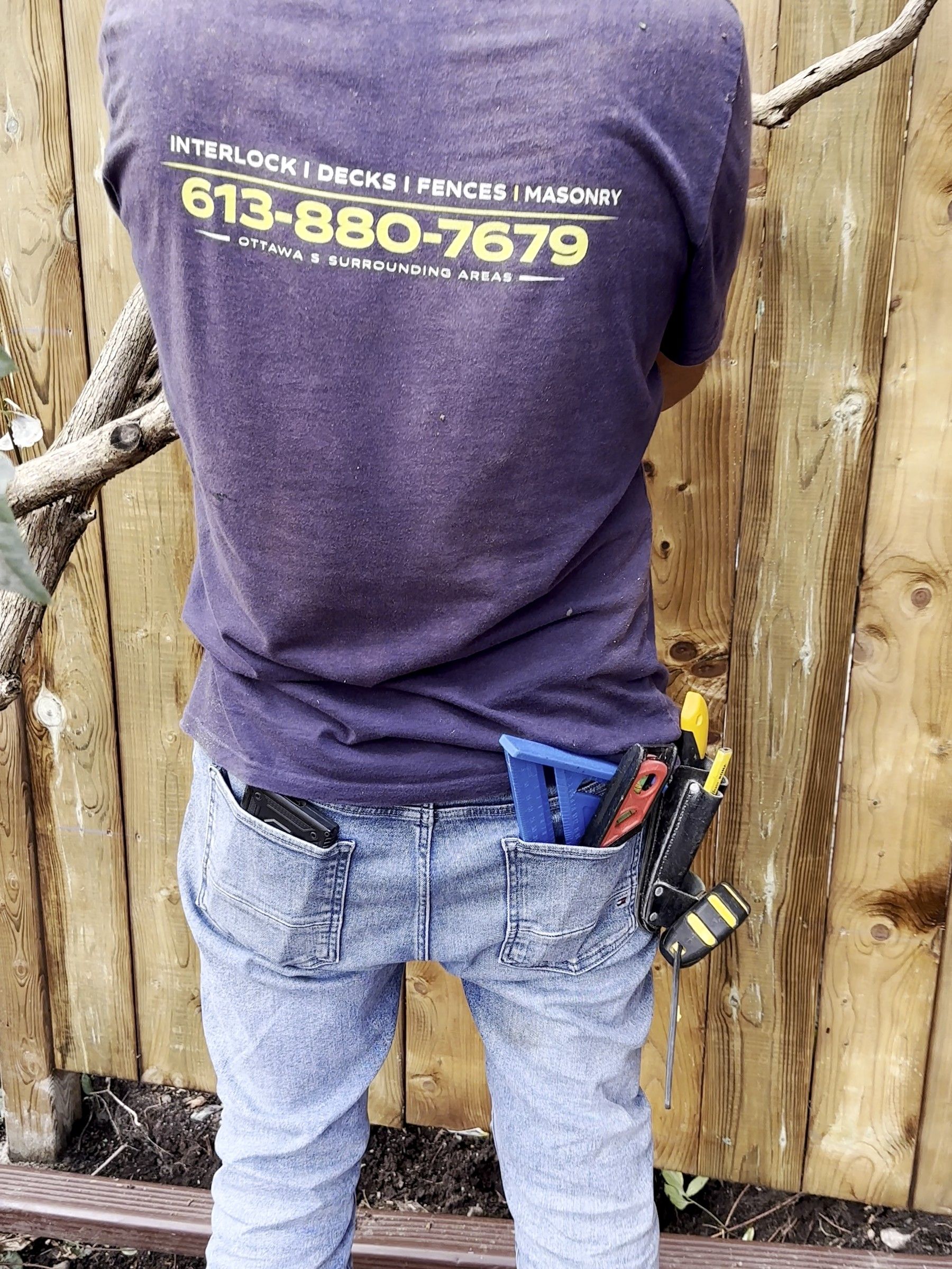 Korvex crew member in a company shirt working on a new board fence