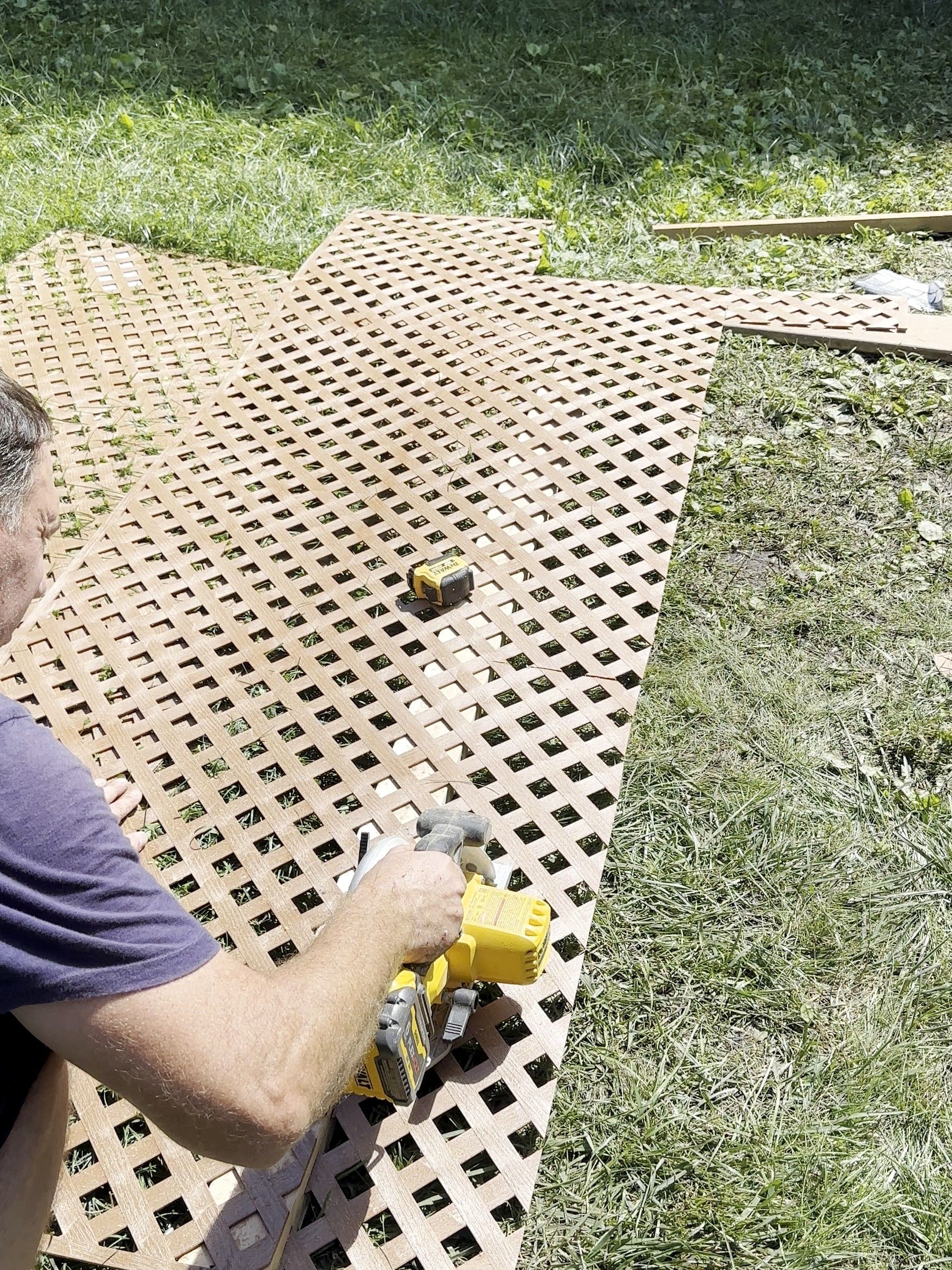 Korvex crew member cutting lattice panels on the lawn with a circular saw