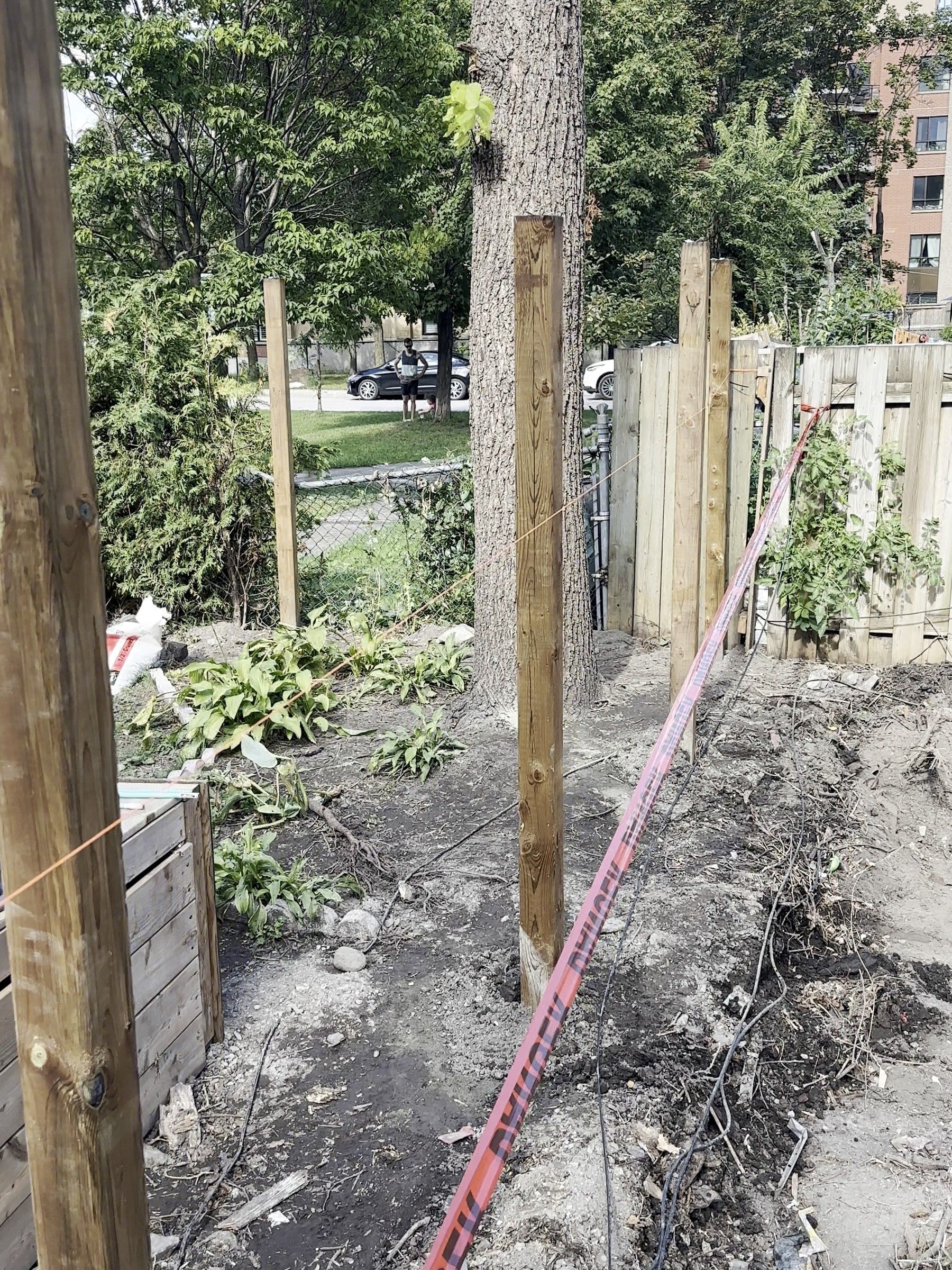 New fence posts set to a red string line across a backyard