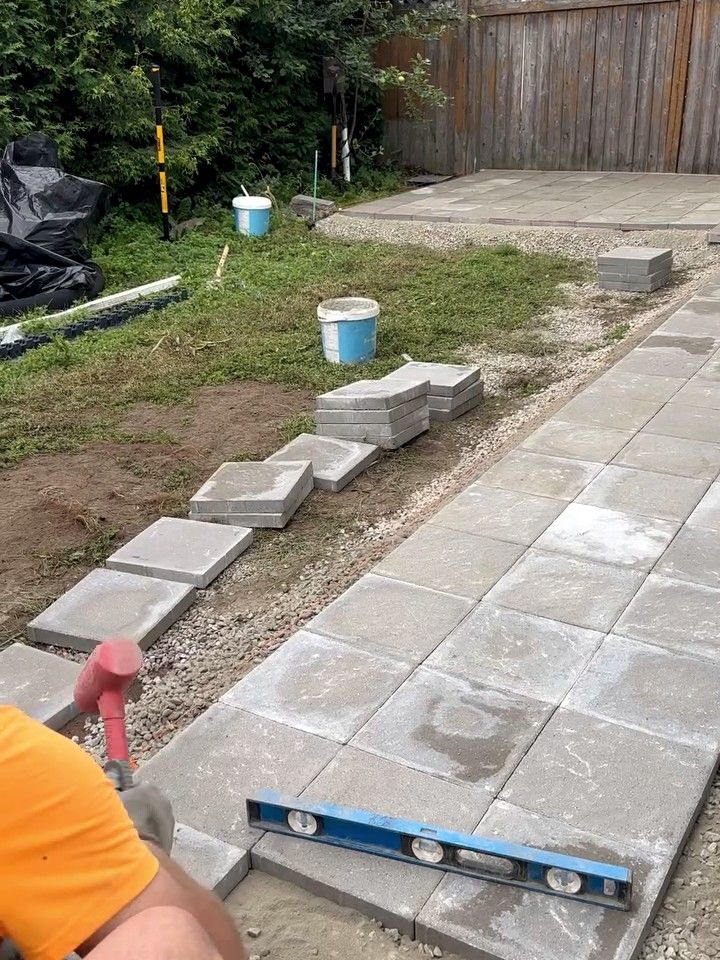 Walkway slabs being set along a house, with a level resting on them